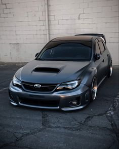 a grey car parked in front of a white brick wall