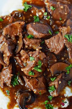 a close up of food on a plate with broccoli and mushrooms in gravy