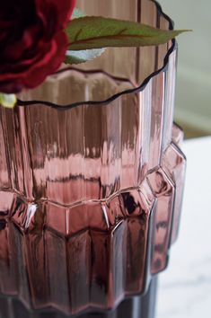 a pink vase with a red rose in it