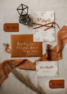 the wedding stationery is laid out on top of each other, including an orange ribbon