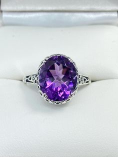 Natural Purple Amethyst Ring  Edward Design#70z (smaller version) MADE TO ORDER Inspired by Edwardian jewelry of the early 1900s, I now offer this lovely Antique reproduction ring in sterling silver. This gorgeous ring is set with a stunning 3.32ct Natural purple amethyst gemstone. This genuine amethyst has excellent color and clarity. The oval cut amethyst is 12mm (1/2th of an inch) Long by 10mm Wide (3/8th"). The ring sits 6mm off the finger. The inside of the band s marked 925 for sterling. W Oval Purple Filigree Amethyst Ring, Purple Oval Amethyst Ring With Filigree, Oval Purple Amethyst Ring With Filigree, Purple Oval Filigree Rings, Classic Oval Amethyst Ring With Accent Stones, Oval Amethyst Ring With Intricate Design, Oval Amethyst Ring With Center Stone, Oval Amethyst Filigree Ring For Wedding, Oval Amethyst Ring With Filigree Detail