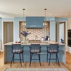 a kitchen with blue and white walls, wooden floors and stools in front of the island