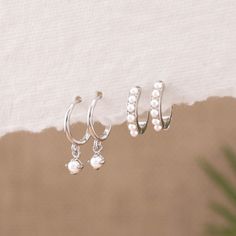 Meet your new everyday treasure: the Dainty Drop Pearl Matching Hoop Gift Set! These perfect pearl hoops are a versatile addition to your stacking hoops collection, thanks to the ideal 8mm and 9mm hoop sizes and tiny ivory pearls that illuminate your everyday look. Made with solid sterling silver, an 18K gold finish, and quality pearls, they are hypoallergenic and water-resistant. Choose a gift set of one or two pairs for your bridesmaids, sister, or loved ones--including yourself! This pearl jewelry will add classic, understated elegance to any outfit. - Material: Hypoallergenic, Solid 925 sterling silver and 18K gold filled finish  Huggie inner diameter: 8.5mm (Style A) / 9mm (Style B) - Turnaround time: Same day or Next day delivery guaranteed  - Qty: Sold as 1 or 2 PAIRS (1 PAIR = 2 EA Stackable Sterling Silver Huggie Earrings As Gift, Dainty Silver Huggie Earrings For Wedding, Delicate Sterling Silver Huggie Earrings For Wedding, Dainty Sterling Silver Huggie Earrings For Wedding, Sterling Silver Stackable Huggie Earrings As Gift, White Gold Stackable Earrings As Gift, Delicate White Hypoallergenic Huggie Earrings, Dainty Small Hoop Cartilage Earrings For Wedding, Sterling Silver Hoop Earrings With Pearl Charm As Gift