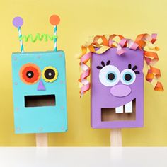 two popsicles decorated to look like monsters with eyes and noses on them, one is purple and the other is blue