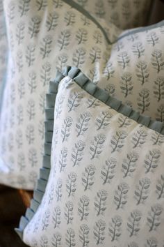 two pillows sitting on top of a wooden chair next to each other with blue and white designs