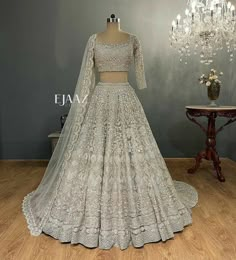 a wedding dress on display in a room with chandelier and vases filled with flowers