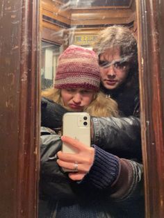 a man and woman taking a selfie in front of a mirror with their cell phone