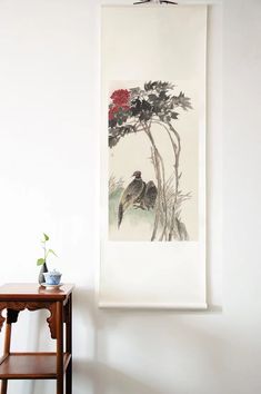 a painting hanging on the wall next to a wooden table with a potted plant