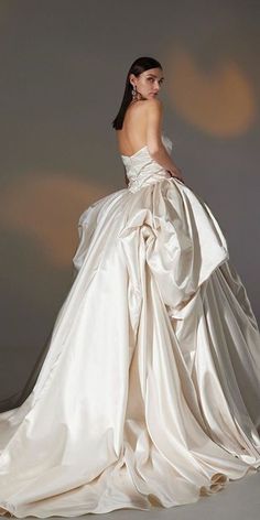 a woman in a white wedding dress is posing for the camera with her back to the camera