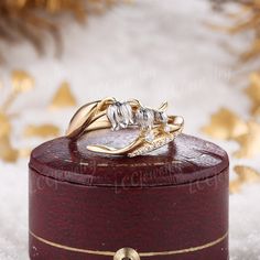 two gold wedding rings sitting on top of a wooden box in the middle of snow