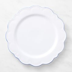 an empty white plate with blue trim on a marble surface