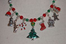 I hand beaded this one-of-a kind Holiday necklace with enamel and silver tone metallic Christmas charms and glass and silver tone beads.  The center charm pendant is an enamel and silver Christmas tree topped with a lampworked glass star bead. The other eight charms are a Santa hat, a snowman, a reindeer, candy canes, a Christmas stocking, an old-time Santa, a gingerbread man, and Santa's sleigh.  Happy Holidays This necklace has a J-hook clasp and is lightweight and comfortable to wear. Ours is a non-smoking home. Beaded Jewelry For Christmas Holiday, Gift Silver Beads Dangle Necklaces, Silver Beaded Necklaces With Dangling Beads For Gifts, Silver Beads Dangle Beaded Necklaces As Gift, Beaded Jewelry For Christmas Celebrations, Festive Beaded Holiday Jewelry, Handmade Christmas Necklaces For Festive Occasions, Christmas Gift Beaded Necklaces With Round Beads, Silver Holiday Necklaces For Festive Occasion