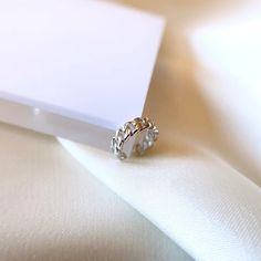 a close up of a ring on a white cloth with a piece of paper in the background