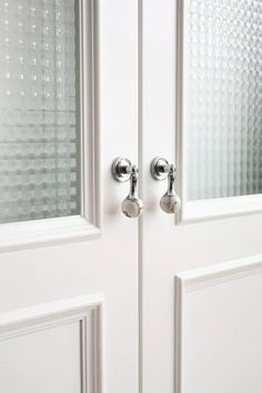 two white double doors with chrome handles and glass panels on the front door are shown