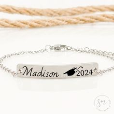 a bracelet with the name madison on it and a graduation hat charm in black ink