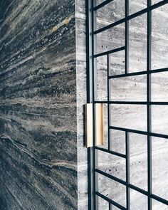 an image of a marble wall with metal grates on it's sides and a gold door handle in the middle