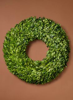 a round boxwood wreath hanging on a wall in the shape of a circle with leaves