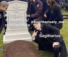 a man sitting on the ground in front of a grave with other people around him