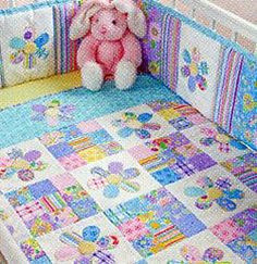 a pink teddy bear sitting on top of a crib next to a quilted blanket