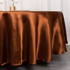 the table is covered with an orange satin cloth and has two wine glasses on it