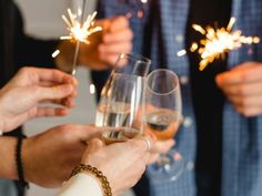 people holding wine glasses with sparklers in their hands