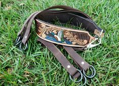 a pair of scissors sitting on top of a brown leather case in the middle of some grass