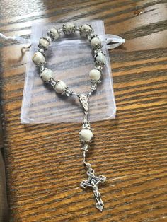 a rosary with a cross on it sitting on top of a wooden table in front of a package