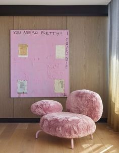 a pink chair sitting in front of a painting