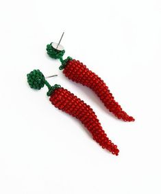 two red beaded carrots sitting next to each other on top of a white surface