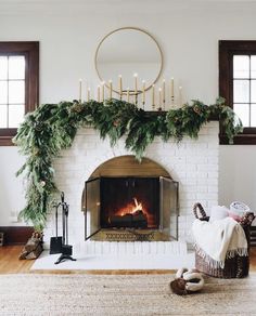 the fireplace is decorated for christmas with greenery on top and candles in the middle