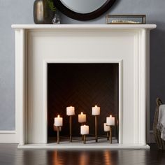 a white fireplace with lit candles in front of it and a mirror on the wall