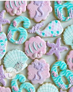 decorated cookies are arranged in the shape of mermaids and seashells on a table