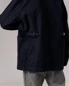 The Recycled Cotton Denim Jacket is a heavy-weight denim chore coat. The jacket features a folded collar, button front, pocket with a pen holder on the left breast, buttoned size adjusters on the back, and dual wraparound pockets at the waist on each side. The material is a 12.6oz recycled denim with reinforced stitching. Indigo Relaxed Fit Denim Jacket, Washed Indigo Cotton Denim Jacket, Washed Blue Single-breasted Denim Outerwear, Pre-washed Indigo Cotton Outerwear, Faded Pre-washed Cotton Denim Jacket, Chore Coat, Black Denim Jacket, A Pen, Recycled Denim