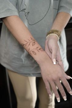 a woman's hand with a small tattoo on her left wrist and the other arm