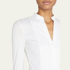 Akris punto blouse in cotton poplin, featuring a jersey back. Split neckline. Long sleeves. Hem hits hips. Fitted. Cotton. Made in Italy. Classic Tops For Workwear, Modern Stretch Tops For Formal Occasions, Modern Formal Stretch Tops, Modern Stretch Blouse For Workwear, Fitted Elastane Tops For Office, Formal Long Sleeve Elastane Tops, White Stretch Tops For Business Casual, Modern Stretch Tops For Business Casual, Formal Fitted Top In Elastane