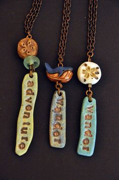 three necklaces with different designs on them sitting on a black surface, one has a bird and the other is an owl