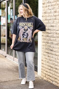 a woman is walking down the sidewalk wearing a rock'n roll t - shirt