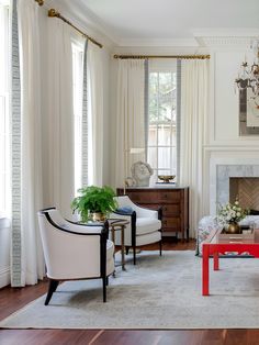 a living room filled with furniture and white drapes on the window sills