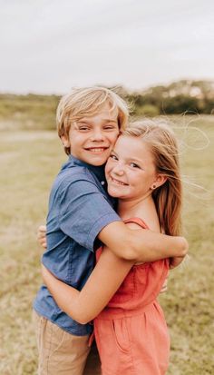 two children hugging each other in an open field