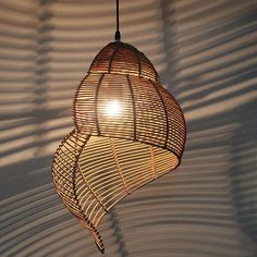 a lamp hanging from the ceiling in a room with shadows on the wall behind it