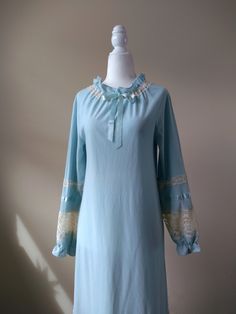 "Vintage sky blue fleece nightgown by Gossard Artemis. Features high ruffled neckline with center ribbon, ruffled cuffs, and lace and satin detailing throughout. Constructed from a warm fleece material. Era: Circa 1960s Condition: Excellent Size: Petite Color: Blue, ivory Brand: Gossard Artemis Measurements: 16in pit to pit, 23in sleeve length, 53in length Fabric Content: 100% nylon (body); 100% polyester (lace) Shown on a mannequin with a 33\" bust, 26\" waist, and 35\" hips. Fits a size 2-4. Model is 5'5 with a 34A bust. Some garments may be clipped onto mannequin or model for display. MORE INFO: *Please, note that all items are vintage. Therefore, it is expected to find some wear. Ariessence by Ariel is an admirer of fashion history and hopes you can appreciate this garment and its char Blue Long Sleeve Bedtime Dress, Blue Long Sleeve Dress For Pajama Party, Long Sleeve Ruffled Nightgown For Loungewear, Long Sleeve Blue Nightgown For Sleepover, Blue Long Sleeve Nightgown For Sleepover, Feminine Blue Sleepwear For Pajama Party, Light Blue Long Sleeve Nightgown For Bedtime, Blue Long Sleeve Nightgown For Pajama Party, Elegant Light Blue Sleepwear For Loungewear