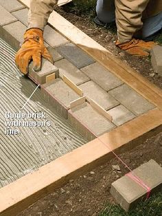 a man laying bricks on the ground to lay them into place for concrete blocks that are being laid in