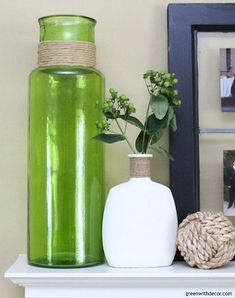 two vases with flowers are sitting on a shelf next to a framed photograph and a rope ball