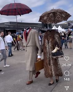 a man and woman dressed in animal print walking under umbrellas at an outdoor event