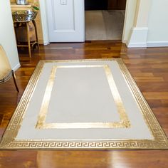 a white and gold area rug in the middle of a wooden floored entry way