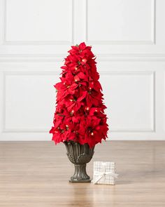 a vase filled with red poinsettias on top of a hard wood floor