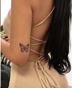 a woman with a butterfly tattoo on her left arm and right arm behind her back