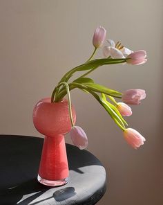 a pink vase with tulips in it sitting on a table