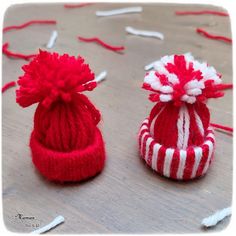 two red and white knitted hats sitting on top of a wooden floor next to each other