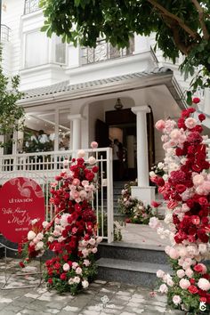 the entrance to a white building with red and pink flowers